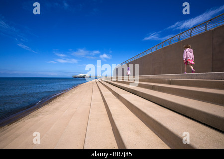 Giovane ragazza dopo la sua madre sui gradini del seawall a Blackpool Foto Stock