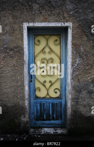 Vecchio Blu porta in legno con sfald vernice e ferro battuto ricoperto la finestra in una casa abbandonata Olot Catalogna Spagna Foto Stock