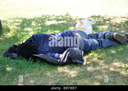 Senzatetto nero uomo dorme in posizione di parcheggio Foto Stock