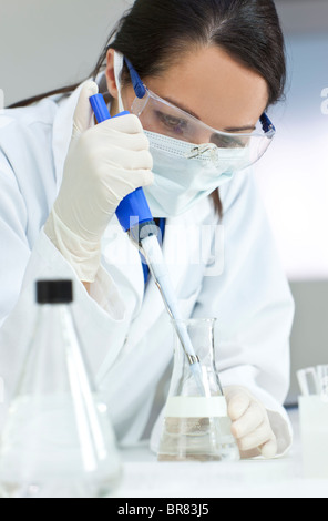 Una femmina di medici o di ricerca scientifica o scienziato usando una pipetta e il pallone in un laboratorio Foto Stock