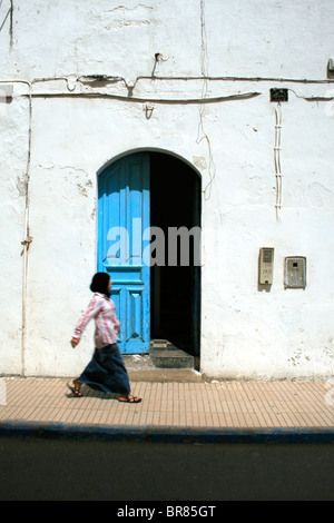 10 settembre 2009; una donna cammina passò un aperto lo sportello blu a Essaouira, Marocco. Foto di David Pillinger. Foto Stock