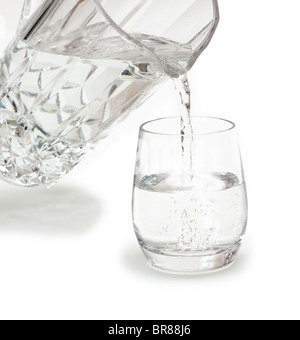 Versando un bicchiere di acqua fresca da una caraffa di cristallo Foto Stock