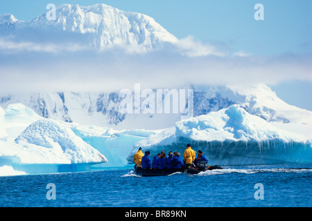 I turisti in una nervatura zodiac davanti di iceberg con bassa cloud, l'Antartide. Foto Stock