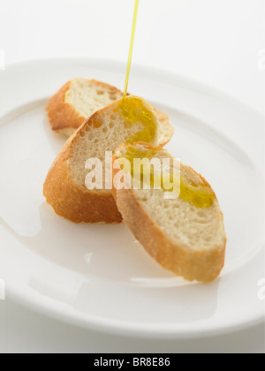 Olio d'oliva venga versato su baguette Foto Stock