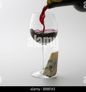 Vino rosso versando in erba, sfondo bianco Foto Stock