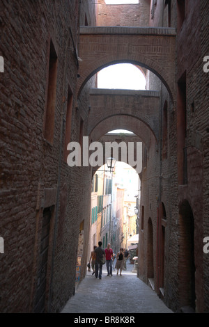 Persone che camminano giù il vicolo stretto, Siena, Italia Foto Stock