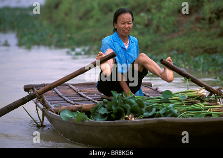 Donna remare una barca con i suoi piedi vicino Tam Coc Vietnam. Foto Stock