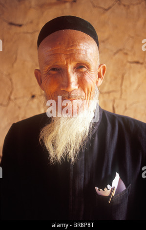 Un anziano uomo Uighur pone per un ritratto in remoto villaggio di Tuyoq Cina. Foto Stock