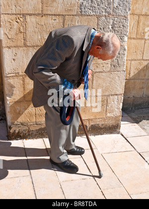 Vecchio sospetto-back uomo con bastone da passeggio in appoggio sul marciapiede - Francia. Foto Stock