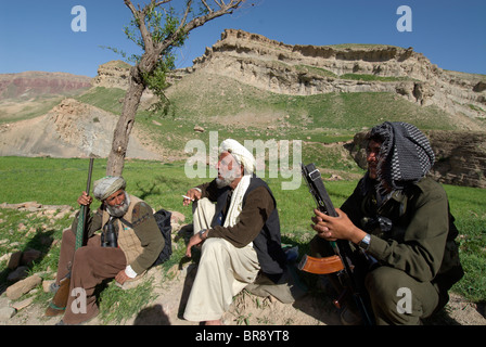 Un cacciatore locale colloqui alla arbob o leader di Dera Jawal villaggio sul bordo di un campo mentre un soldato guarda nel divieto Foto Stock