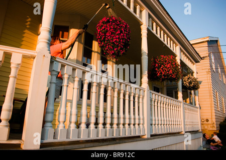 Acque donna fiori sotto il portico della sua casa di Old Orchard Beach in Portland Maine Foto Stock