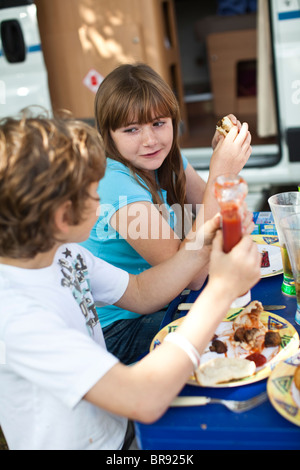 Fratello e Sorella di mangiare la prima colazione insieme al di fuori del loro motorhome in un caravan park, Poole, Dorset, Regno Unito Foto Stock