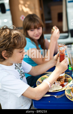 Fratello e Sorella di mangiare la prima colazione insieme al di fuori del loro motorhome in un caravan park, Poole, Dorset, Regno Unito Foto Stock