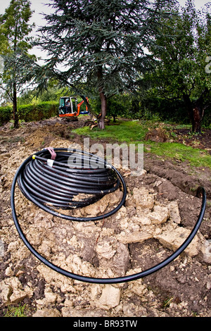 I tubi per il riscaldamento geotermico sistema essendo scavato da un escavatore meccanico Foto Stock