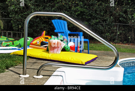 Piscina per bambini Piscina floater giocattoli esplosi gonfiabile di seduta accanto al bordo di un giardino nel cortile con croc shark turtle Foto Stock