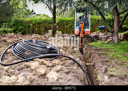 I tubi per il riscaldamento geotermico sistema essendo scavato da un escavatore meccanico Foto Stock
