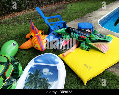 Piscina per bambini Piscina floater giocattoli esplosi gonfiabile di seduta accanto al bordo di un giardino nel cortile con croc shark turtle Foto Stock