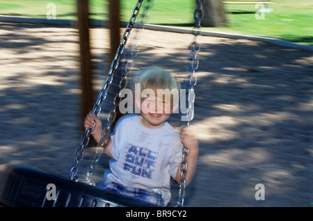 Anni Novanta sorridente ragazzo biondo SULLA ROTAZIONE DEI PNEUMATICI Foto Stock