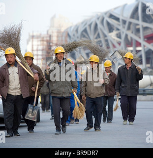 I lavoratori migranti a piedi passato il Bird's Nest Stadium come fanno ritorno ai loro dormitori dopo una giornata di Lena Beij Foto Stock