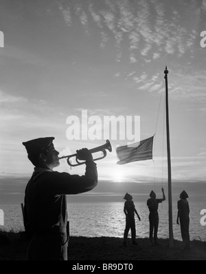 Anni sessanta boy scout A CAMP INFERIORE AL TRAMONTO bandiera americana BUGLE rubinetti 4 ragazzi stagliano uniforme Foto Stock