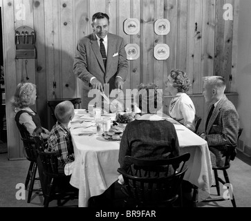 Degli anni Cinquanta padre permanente al tavolo per la cena di pino nodoso PANNELLATA SALA DA PRANZO pronto a servire la famiglia e scolpire LA TURCHIA Foto Stock