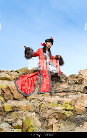 Giovane uomo asiatico in abito mongolo siede sulla roccia Foto Stock