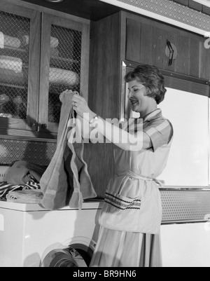 Negli anni sessanta la piegatura donna Servizio Lavanderia Asciugamani su ESSICCATORE IN CUCINA Foto Stock