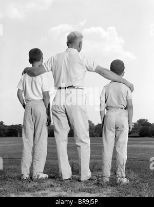 Anni sessanta vista posteriore nonno con due nipoti ragazzi Foto Stock