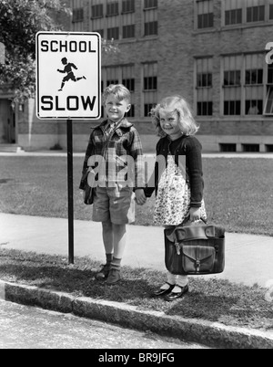 1930s 1940s BOY GIRL Holding Hands accanto alla scuola di segno lento Foto Stock