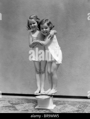 Negli anni Trenta due bambine stando in piedi sulla scala A BRACCETTO sorridente Foto Stock