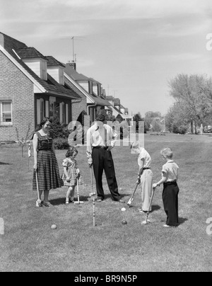 Anni Cinquanta madre di famiglia padre di 3 figli giocare CROQUET prato davanti a casa suburbana Foto Stock