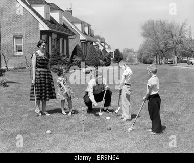 Anni Cinquanta madre di famiglia padre di 3 figli giocare CROQUET prato davanti a casa suburbana Foto Stock