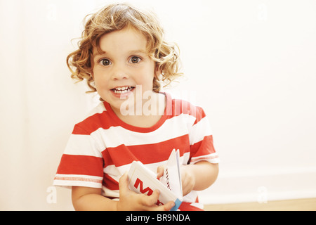 Little Boy in rosso e bianco striato shirt la lettura di un libro Foto Stock