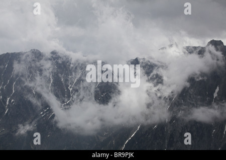 Rising nebbia nube bassa volute intorno Els Encantats peak vista da d'Amitges in Sant Maurici Parco Nazionale Pirenei Spagna Foto Stock