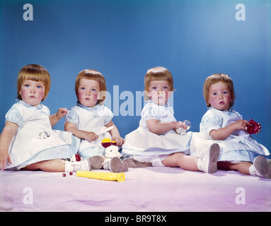 Anni Cinquanta anni sessanta ritratto di gemelle 4 dai capelli rossi le ragazze che indossano abiti seduto in una riga Foto Stock