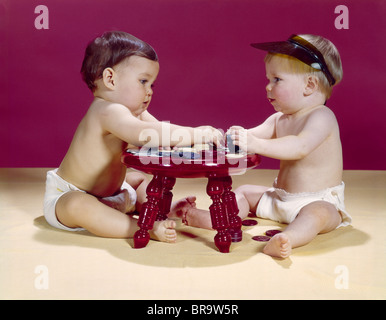 Anni sessanta Due bambini seduti a sgabello rosso carte da gioco POKER CON FICHES Foto Stock