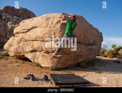 Scalatore maschio bouldering a Joshua Tree National Park, California, Stati Uniti d'America Foto Stock