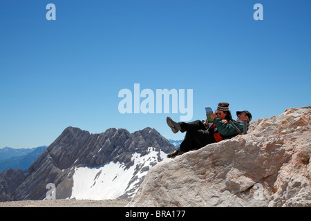 Due alpinisti appoggiati all'altopiano Zugspitzplatt della tedesca Zugspitze prima gli ultimi metri al vertice su un giorno di estate Foto Stock