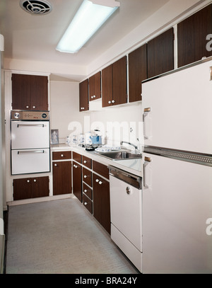 Anni Settanta stretta stile di cucina cucina con legno scuro e armadi di elettrodomestici bianchi Foto Stock