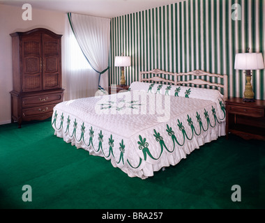 Anni Settanta CAMERA DA LETTO CON verdi e copriletto bianco carta da parati a strisce e luminose tappezzeria verde Foto Stock