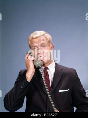 Anni sessanta bionda sorridente imprenditore giovane parlando al telefono retrò Foto Stock