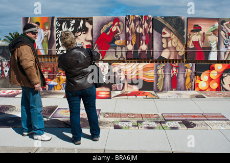 Artista visualizzando la pittura ad un potenziale cliente presso il St Kilda Esplanade mercato domenicale Foto Stock