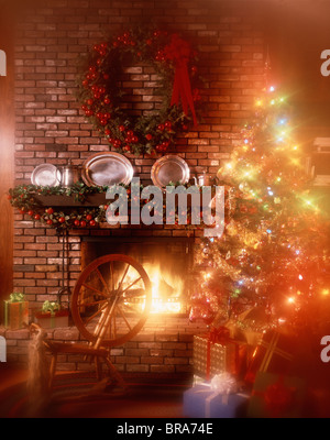 Albero di Natale illuminato da camino decorato MANTEL RUOTA DI FILATURA Foto Stock