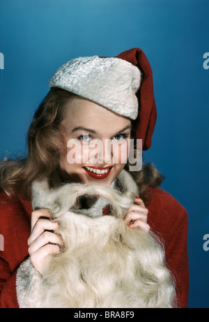 Negli anni quaranta anni cinquanta donna sorridente indossando SANTA CLAUS COSTUME CON Cappello e barba Foto Stock