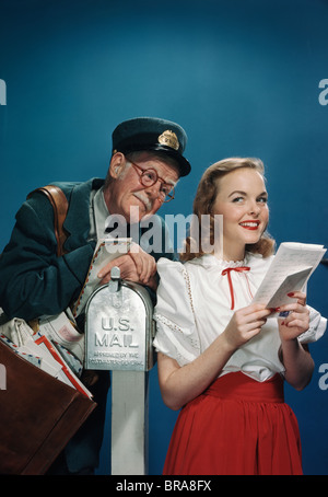 Negli anni quaranta anni cinquanta anziani MAILMAN lettura sopra la spalla del giovane donna AZIENDA LETTERA Foto Stock