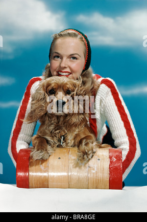 Negli anni quaranta anni cinquanta donna sorridente sulla pista da slittino in legno con cocker spaniel cane Foto Stock