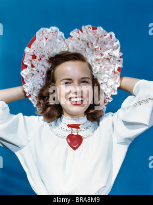 Negli anni quaranta anni cinquanta sorridente ragazza TEEN indossando cuore perno sagomato e arruffata HAT Foto Stock
