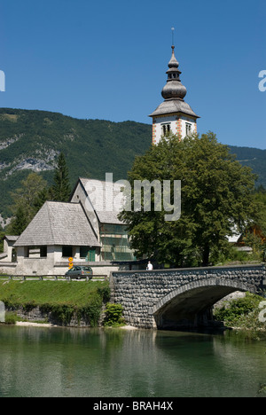 La chiesa nel villaggio, ponte sopra il lago di Bohinj, Slovenia, Europa Foto Stock