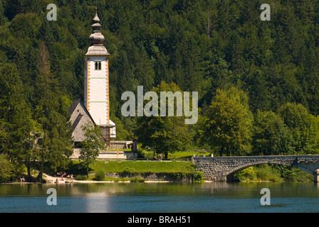 La chiesa nel villaggio, ponte sopra il lago di Bohinj, Slovenia, Europa Foto Stock