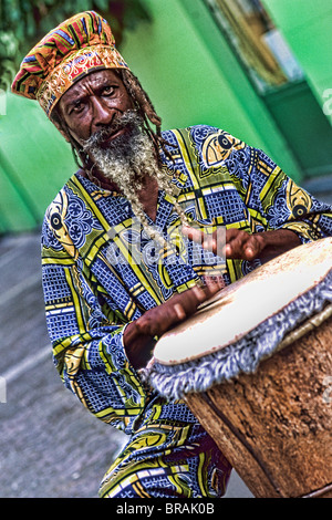 Colorato Rasta reggae giamaicano attore sul tamburo in costume al porto di St John Antigua Foto Stock